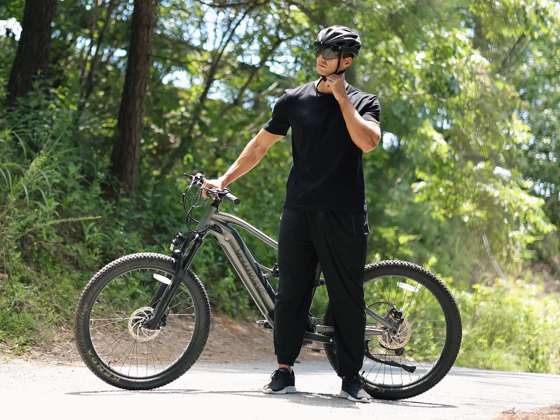 Velowave Forest SM MTB Person standing next to a bicycle on a path with trees in the background. Valowave Forest SM MTB