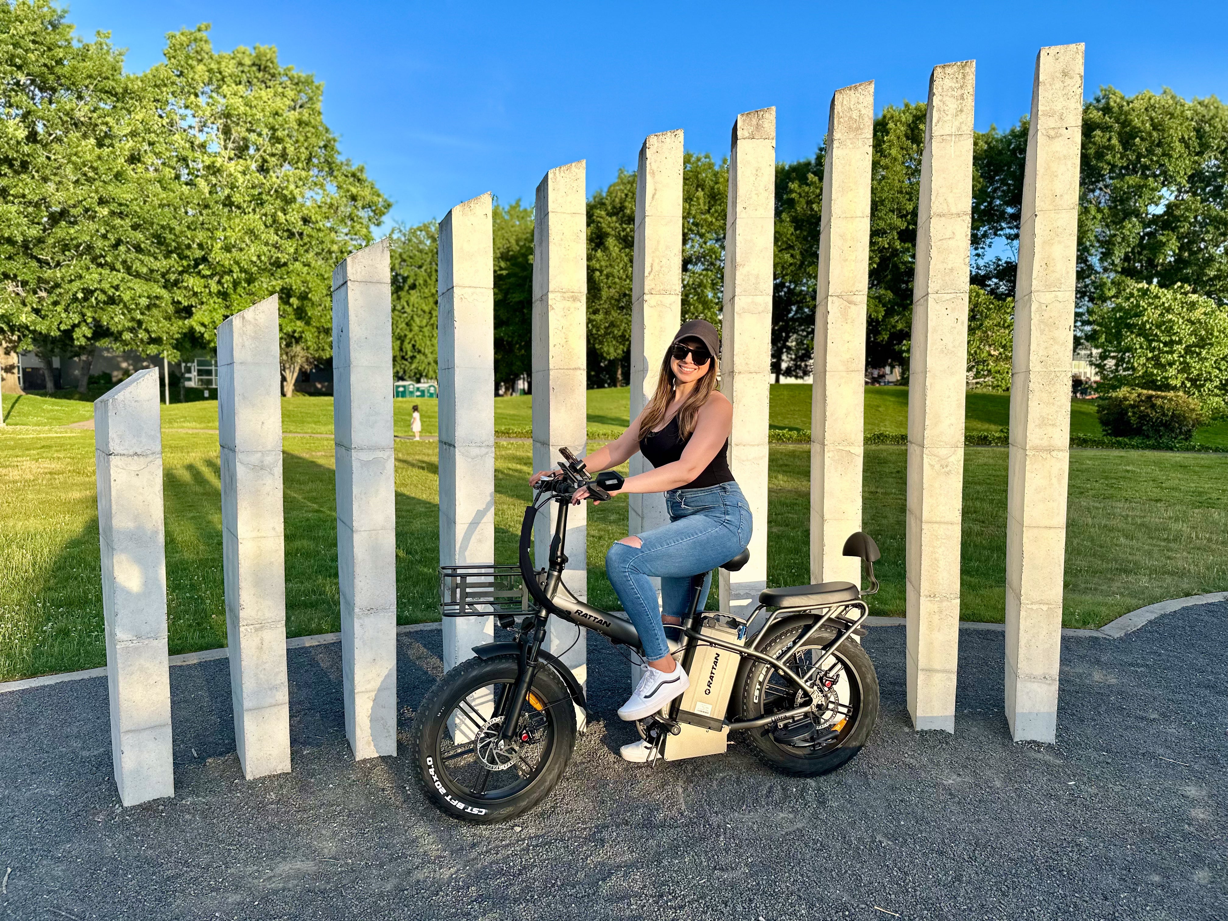 Rattan LM Ultra Folding ebike Person riding a bike in a park with stone pillars and greenery. Rattan LM Ultra Folding ebike