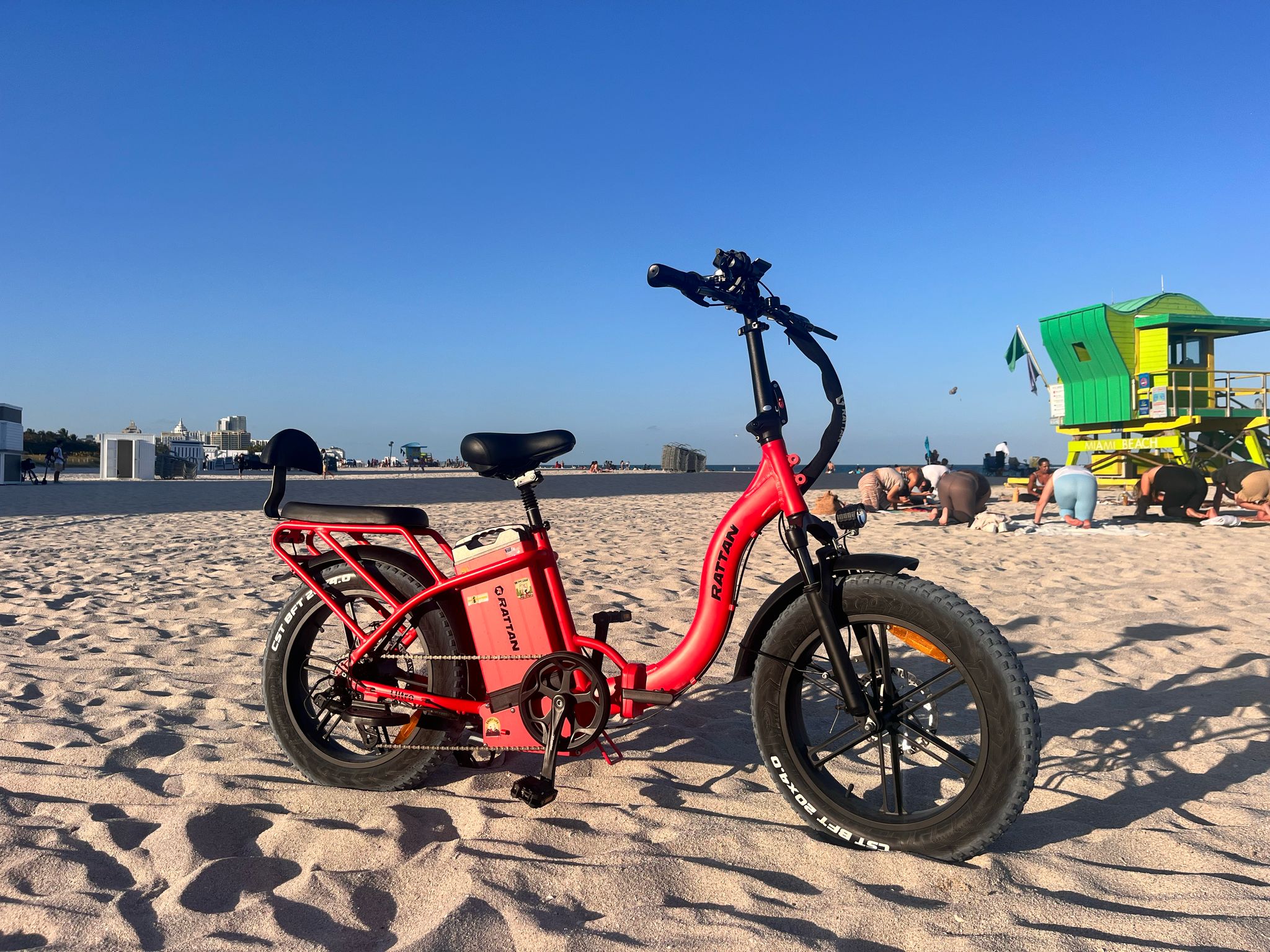 Rattan LF Ultra Folding ebike Red electric bike on a sandy beach with a lifeguard tower in the background. Rattan LF Ultra Folding ebike