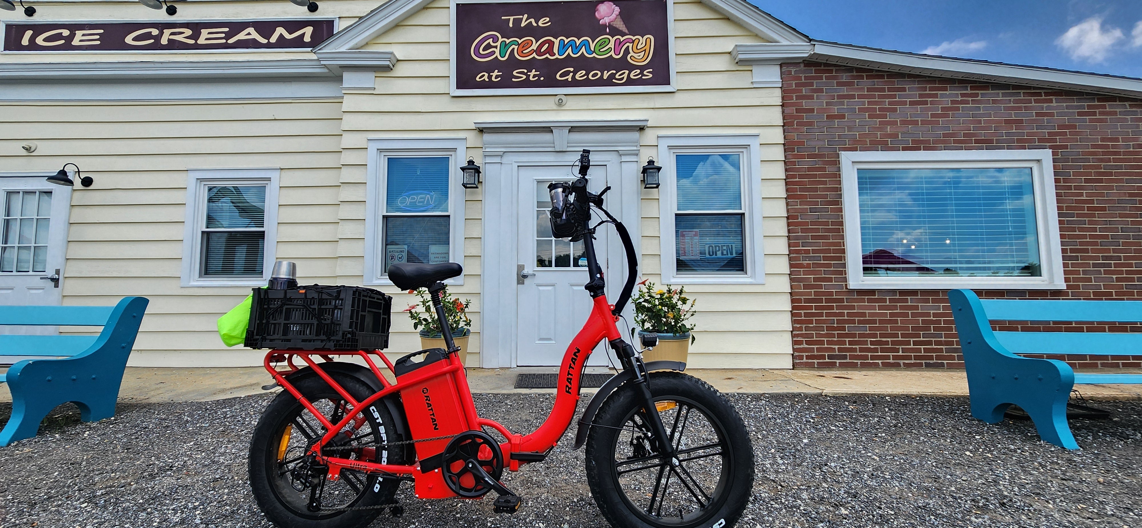 Rattan LF Ultra Folding ebike Red electric bike in front of a building with 'The Creamery at St. Georges' sign. Rattan LF Ultra Folding ebike