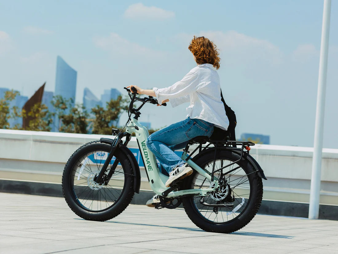 Velowave Ranger Step-Thru 3.0 Torque Sensor Electric Bike Person riding a light blue electric bike on a rooftop with cityscape in the background. Valowave Ranger Step-Thru 3.0 Torque Sensor Electric Bike