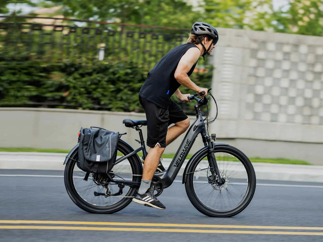 Velowave Breeze T Torque Sensor Electric Bike Person riding a bicycle on a road with a helmet and backpack. Valowave Breeze T Torque Sensor Electric Bike