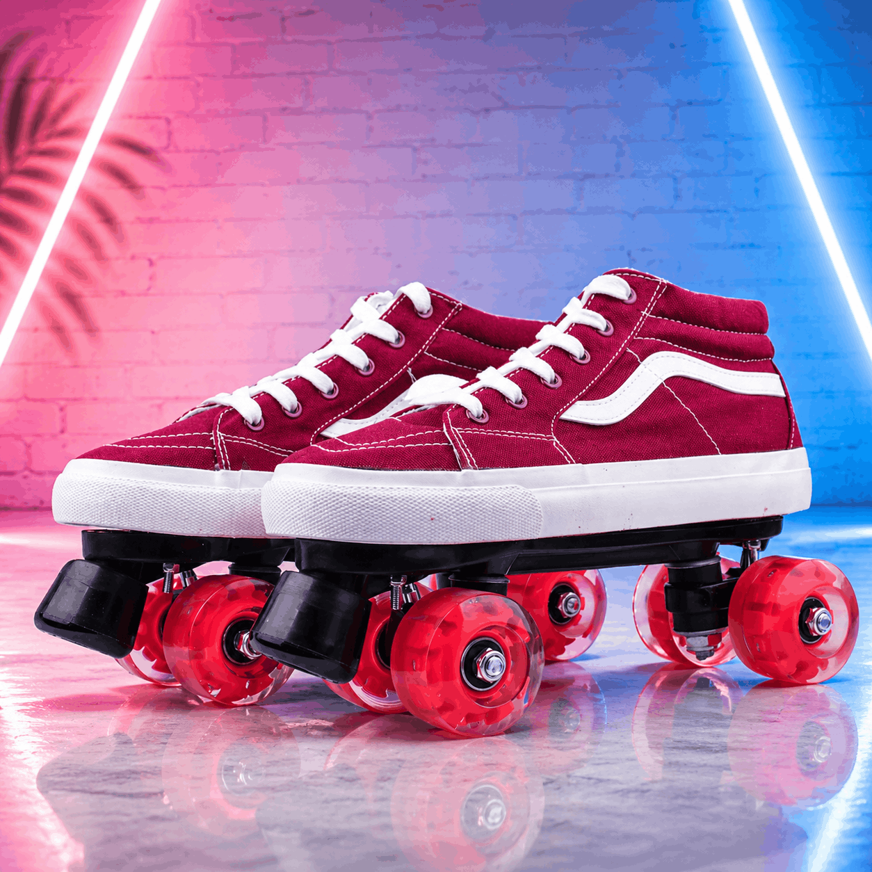 Quad Skating Double Row Roller Skates Red roller skates with white laces on a reflective surface with neon lights in the background.