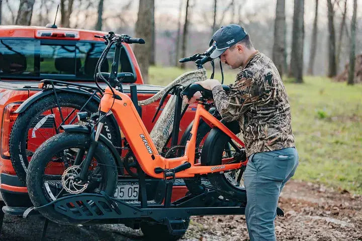 YOUNG Electric E-Flow 750W Folding eBike Man attaching an electric bike to a red SUV in a wooded area. YOUNG Electric E-Flow 750W Folding eBike