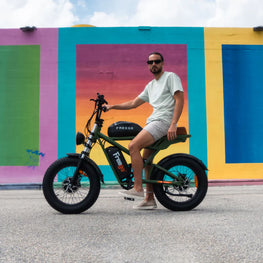 Man sitting on a green electric bike in front of a colorful mural. Freego Flash F3 Pro Dual Motor and Battery eBike