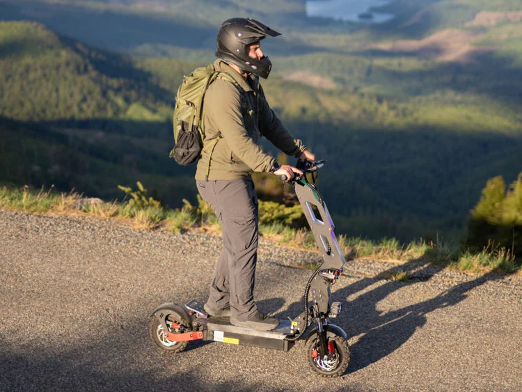 Freego D11 Landtiger Electric Scooter Foldable Dual Motor 4000W Person riding an electric scooter on a mountain road with a scenic background. Freego D11 Landtiger Electric Scooter Foldable Dual Motor 4000W