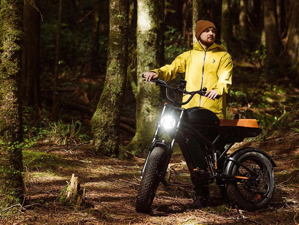 Freego Flash F3 Pro Max Dual Motor and Battery eBike Person in a yellow raincoat standing next to an electric bike in a forest. Freego Flash F3 Pro Max Dual Motor and Battery eBike