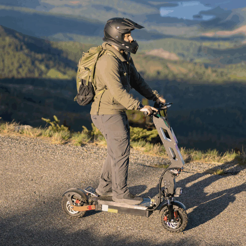 Freego D11 Landtiger Electric Scooter Foldable Dual Motor 4000W Person riding an electric scooter on a mountain road with a scenic view. Freego D11 Landtiger Electric Scooter Foldable Dual Motor 4000W