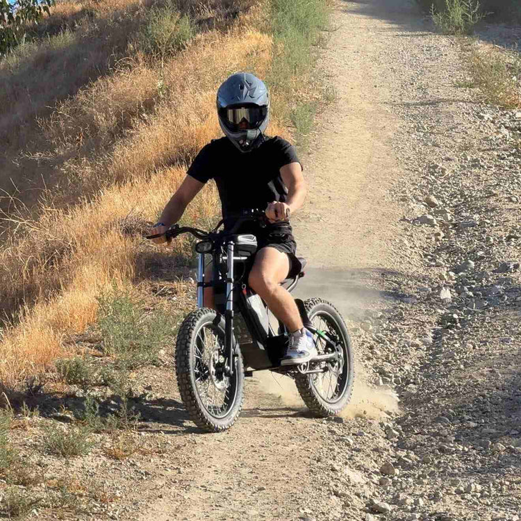 Freego Nova 3 Mid-Drive All-Terrain Dirt eBike Person riding a dirt bike on a gravel path with a helmet on. Freego Nova 3 Mid-Drive All-Terrain Dirt eBike