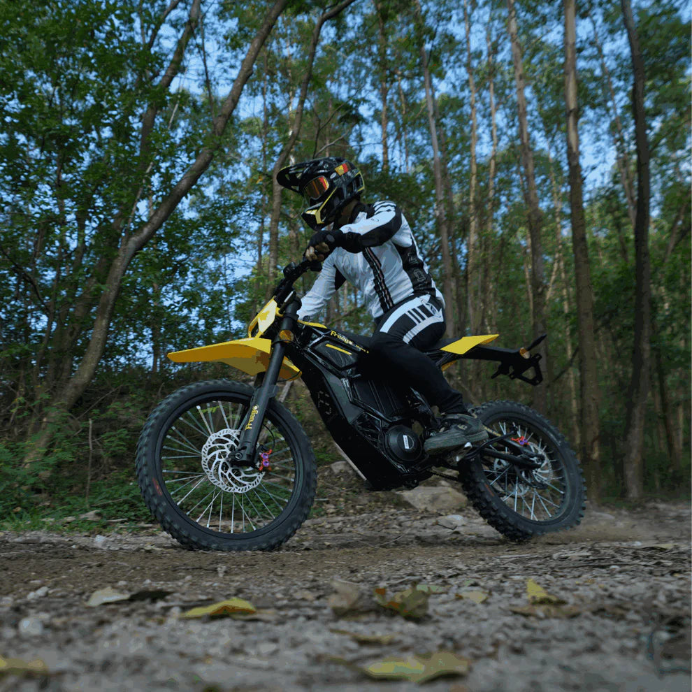 Freego Nova 5 Mid-Drive Off-Road Electric Dirt Bike Person riding a yellow and black dirt bike on a trail in a forest. Freego Nova 5 Mid-Drive Off-Road Electric Dirt Bike