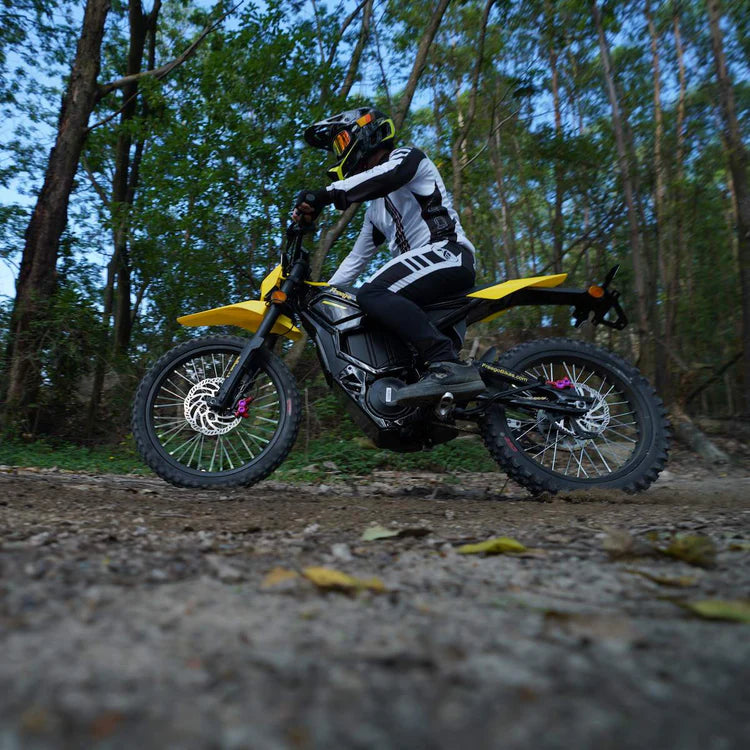 Freego Nova 5 Mid-Drive Off-Road Electric Dirt Bike Person riding a yellow dirt bike on a forest trail.Freego Nova 5 Mid-Drive Off-Road Electric Dirt Bike