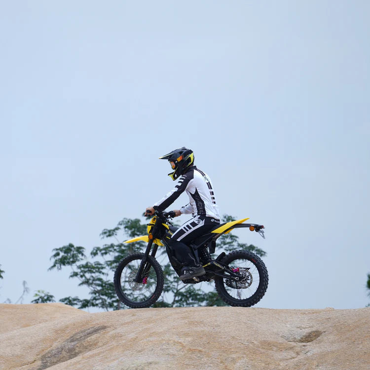 Freego Nova 5 Mid-Drive Off-Road Electric Dirt Bike Person riding a dirt bike on a rocky surface with a clear sky in the background. Freego Nova 5 Mid-Drive Off-Road Electric Dirt Bike
