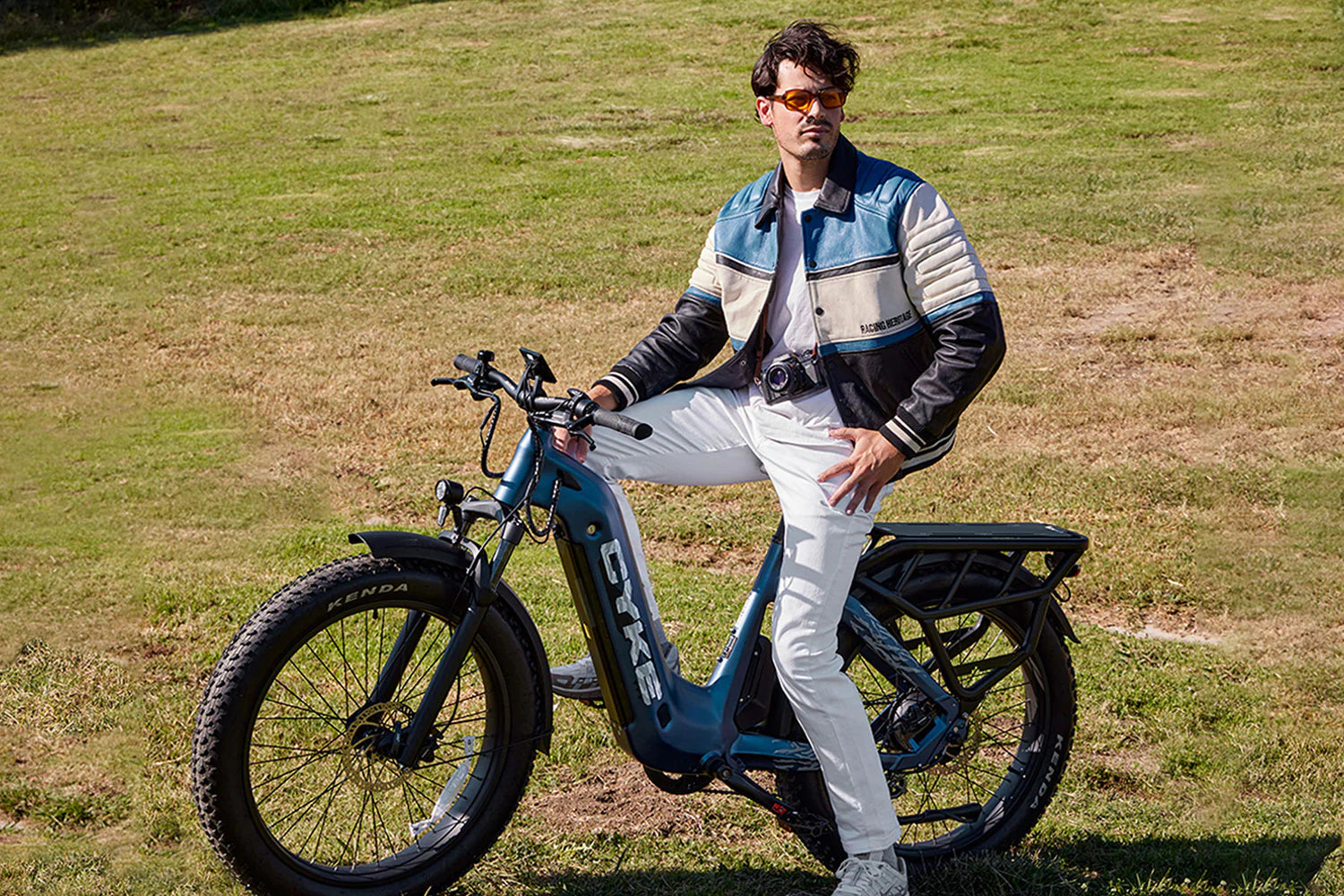 CYKE Lynx Commuter EBike Person sitting on a blue electric bike in a grassy field. CYKE Lynx Commuter EBike