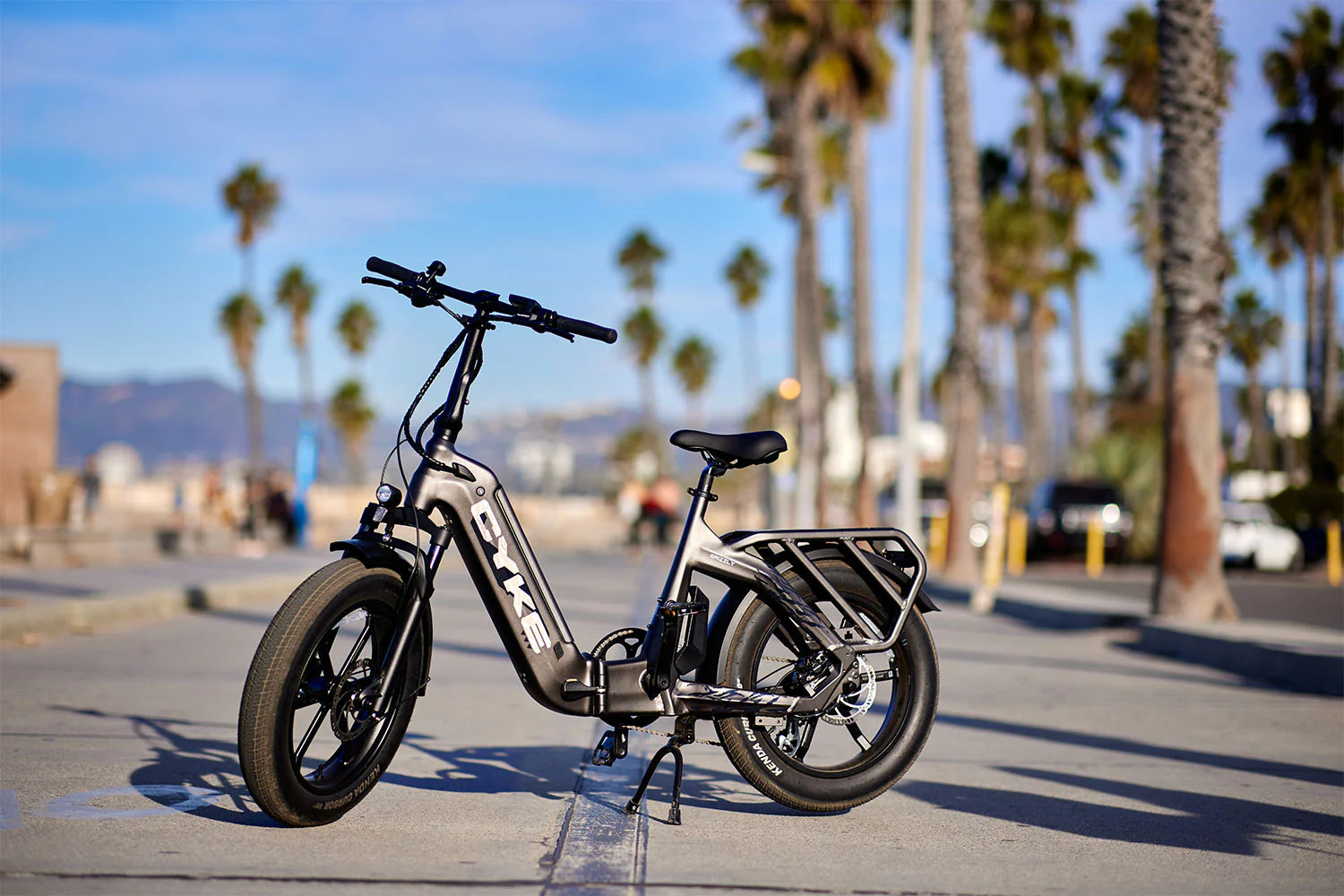 CYKE Grizzly Foldable EBike Electric bike on a sidewalk with palm trees and a clear sky in the background. CYKE Grizzly Foldable EBike