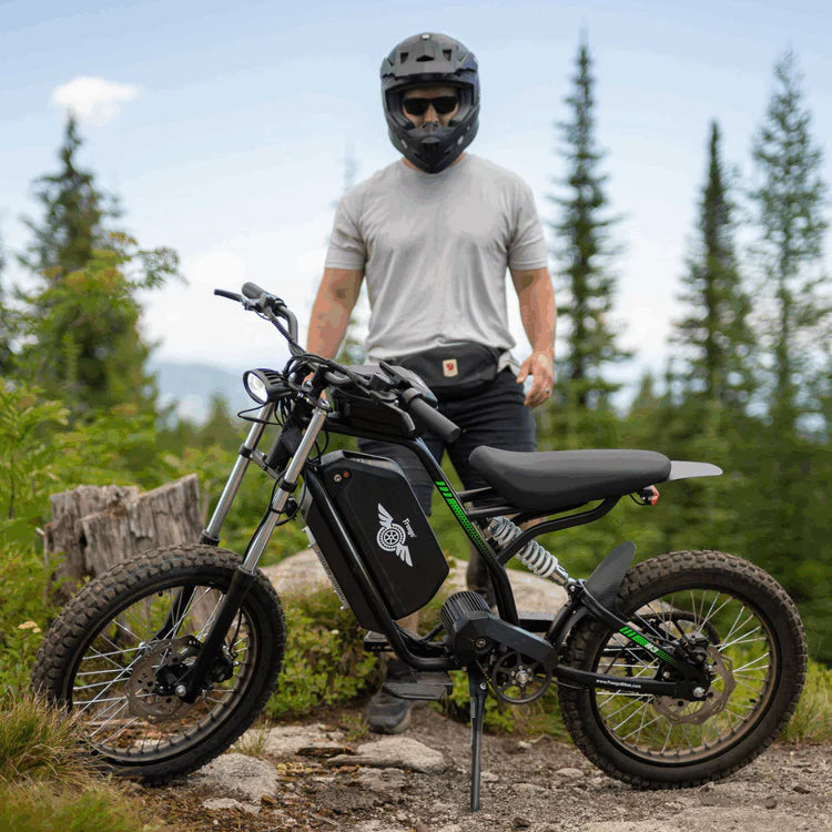 Freego Nova 3 Mid-Drive All-Terrain Dirt eBike Person with a helmet and sunglasses standing next to an electric bike in a forest setting. Freego Nova 3 Mid-Drive All-Terrain Dirt eBike