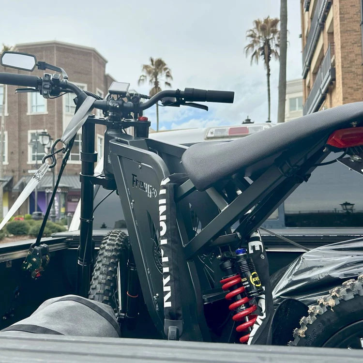 Freego X2 Pro All-Terrain Dirt eBike Electric bike in the back of a truck with buildings and palm trees in the background. Freego X2 Pro All-Terrain Dirt eBike