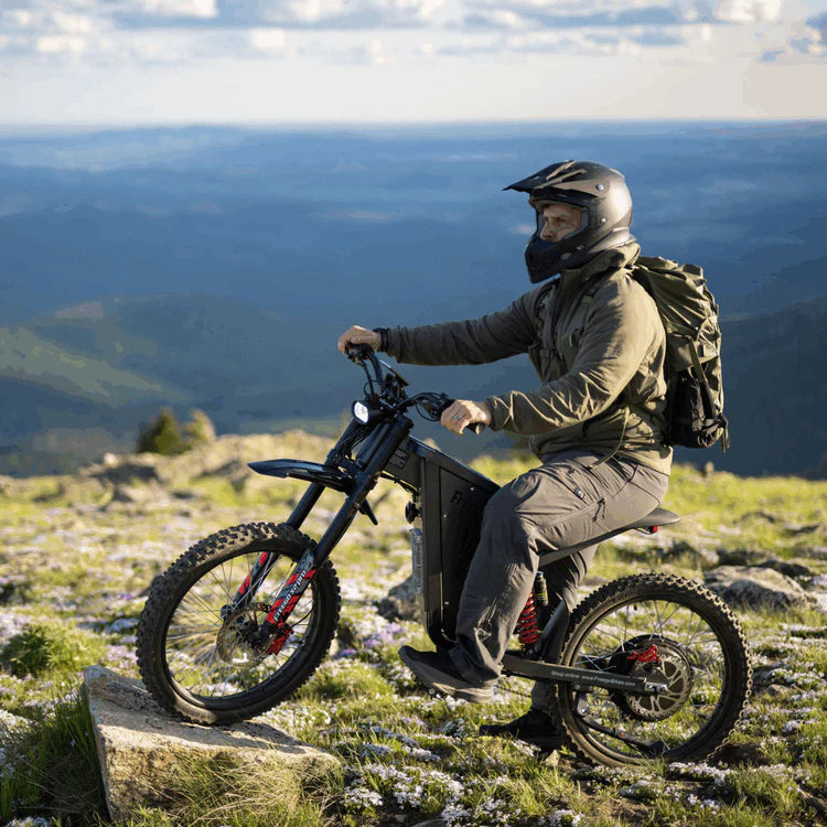 Freego X2 Pro All-Terrain Dirt eBike Person riding a mountain bike on a rocky hill with a scenic view of mountains in the background. Freego X2 Pro All-Terrain Dirt eBike