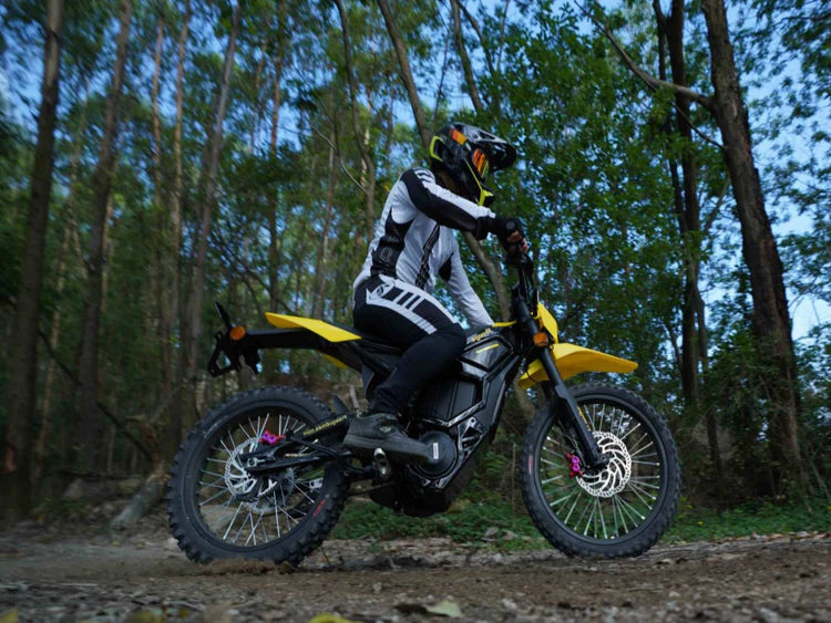 Freego Nova 5 Mid-Drive Off-Road Electric Dirt Bike Person riding a yellow dirt bike in a forest setting. Freego Nova 5 Mid-Drive Off-Road Electric Dirt Bike