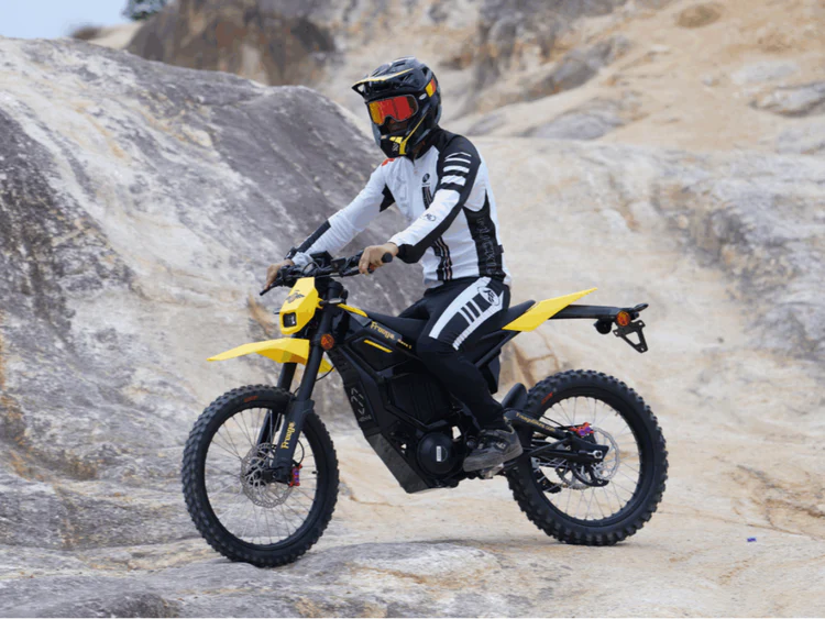 Freego Nova 5 Mid-Drive Off-Road Electric Dirt Bike Person riding a yellow and black motorcycle on rocky terrain. Freego Nova 5 Mid-Drive Off-Road Electric Dirt Bike