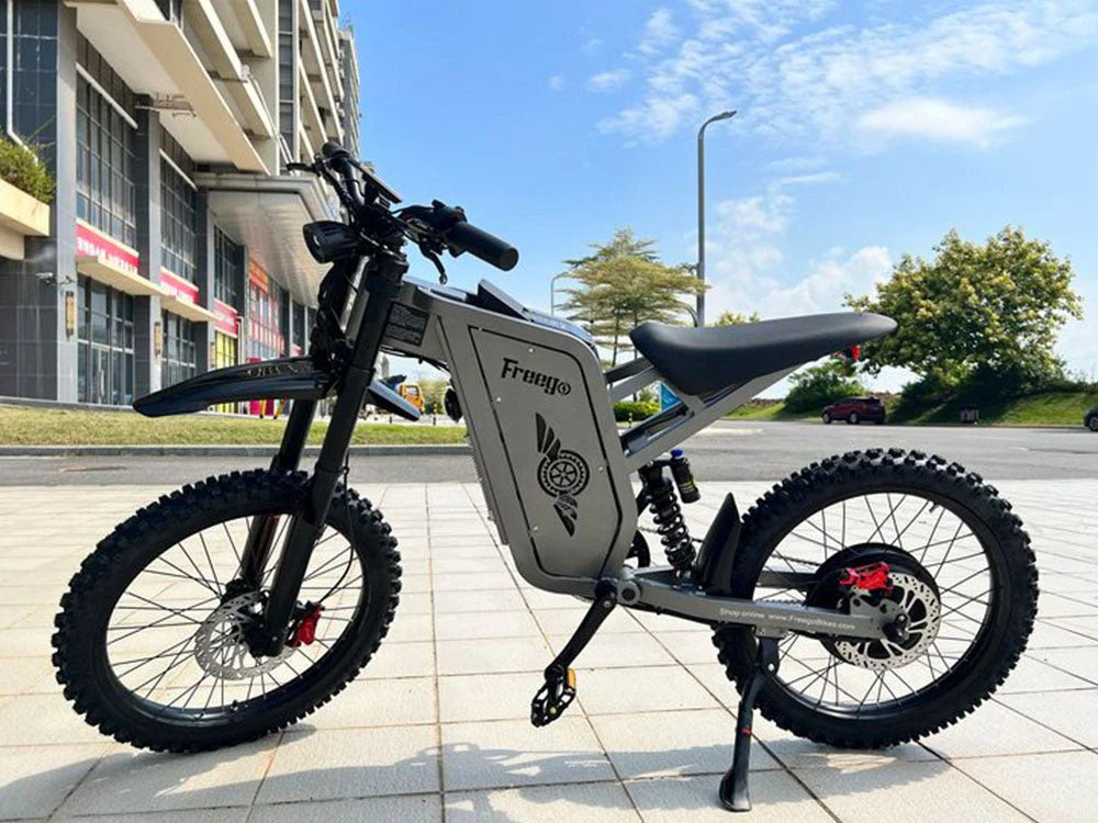 Freego X2 Pro All-Terrain Dirt eBike Electric bike on a sidewalk with buildings and trees in the background. Freego X2 Pro All-Terrain Dirt eBike