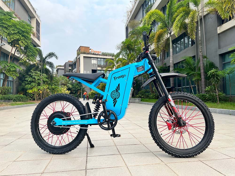 Freego X2 Pro All-Terrain Dirt eBike Blue electric bike on a paved area with buildings and trees in the background. Freego X2 Pro All-Terrain Dirt eBike