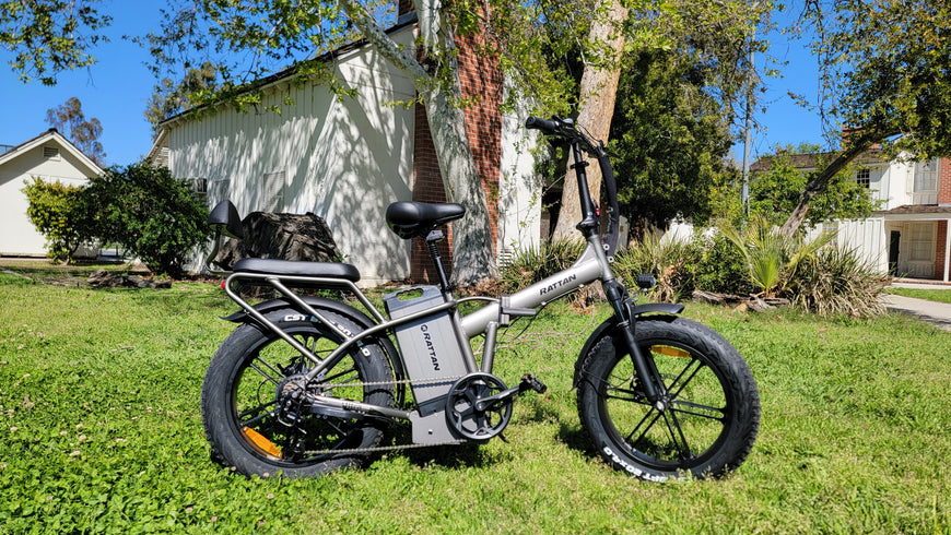Electric bike on grass with a house and trees in the background. Rattan LM Ultra Folding ebike