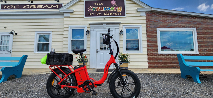Red electric bike in front of a building with 'The Creamery at St. Georges' sign. Rattan LF Ultra Folding ebike