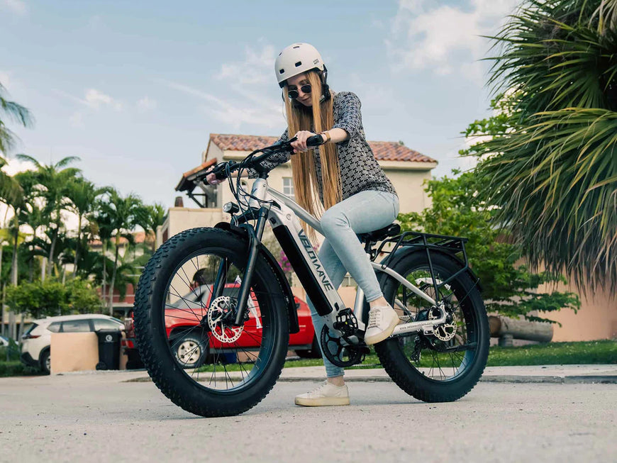 Woman with a helmet on an electric bike in a residential area. Valowave Ranger 2.0 Fat Tire All-Terrain Electric Bike