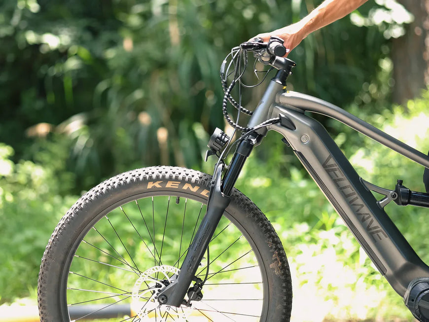 Bicycle with a hand on the handlebar, set against a natural background. Valowave Forest SM MTB