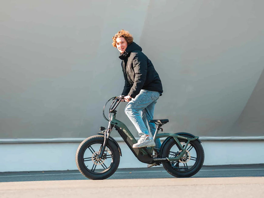 Person riding an electric bike on a road with a plain background. Valowave Pony Compact Step-Thru Electric Bike