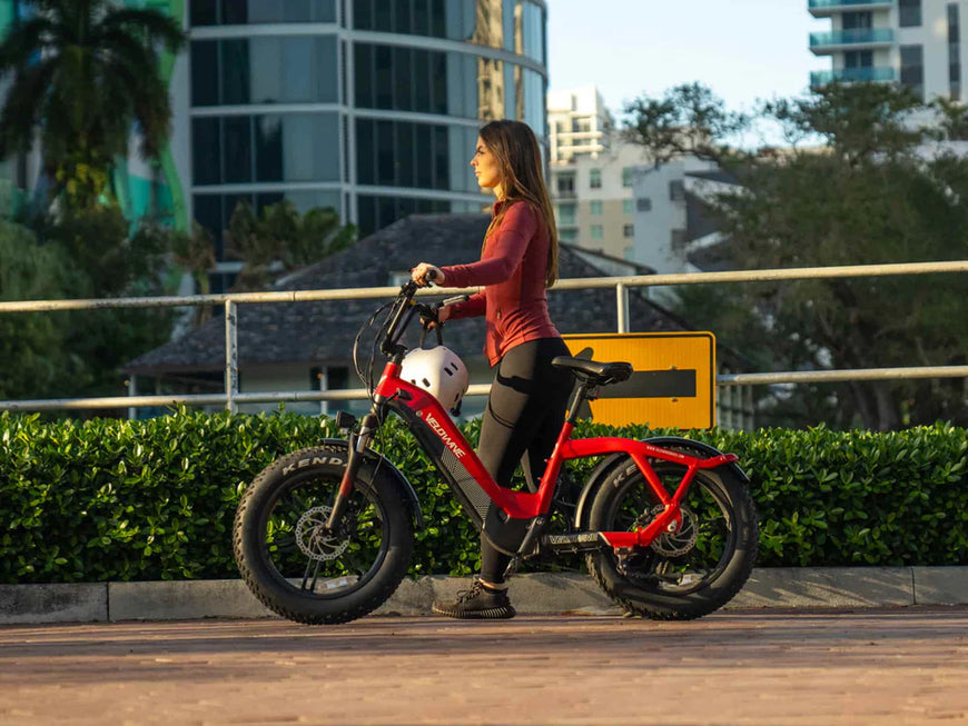 Woman with a red electric bike in an urban setting. Valowave Pony Compact Step-Thru Electric Bike