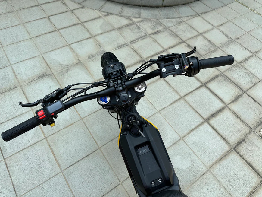 Close-up of an electric scooter's handlebar on a tiled pavement. Natkie N1 All-Terrain Electric Motorcycle
