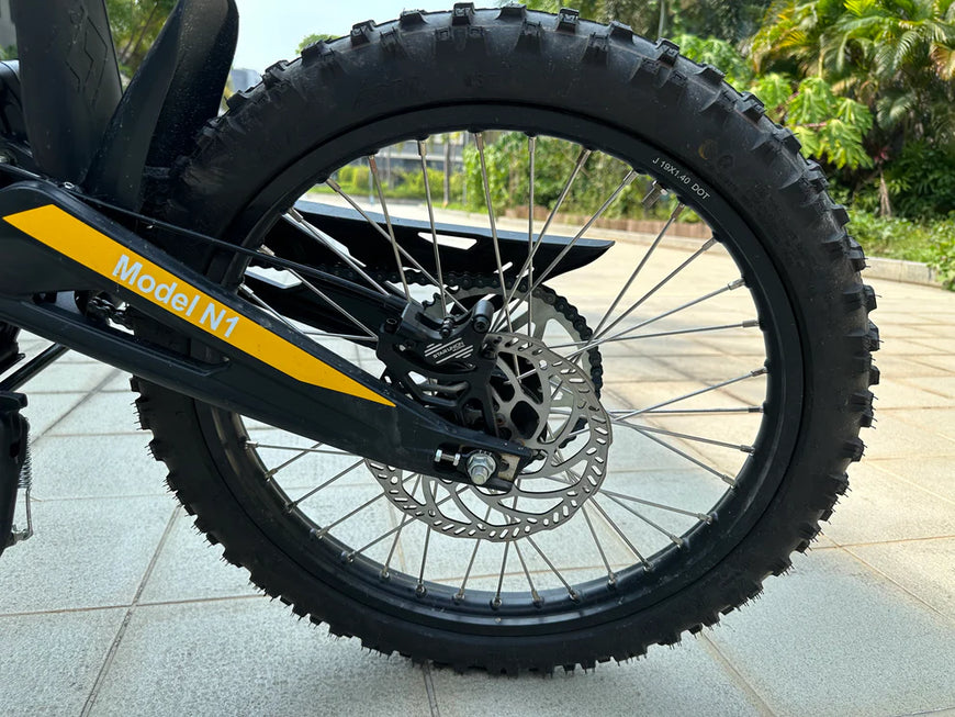 Close-up of a bicycle wheel with 'Model N1' branding on a tiled floor. Natkie N1 All-Terrain Electric Motorcycle