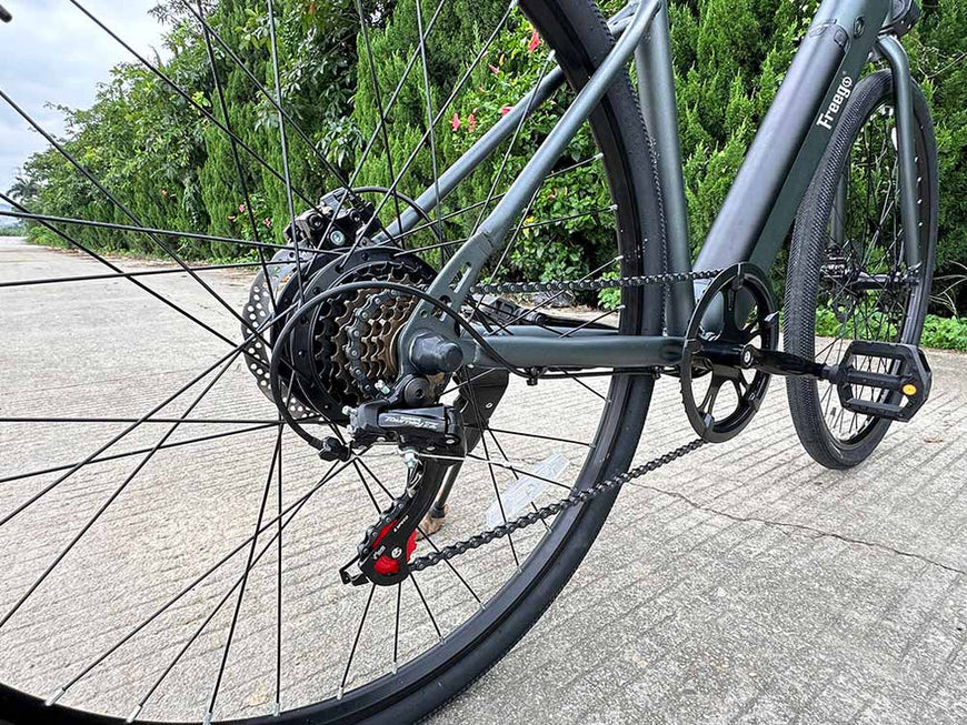 Close-up of a bicycle's rear wheel and gear system on a paved path with greenery in the background. Freego E7 Electric Bicycle For City Commuting