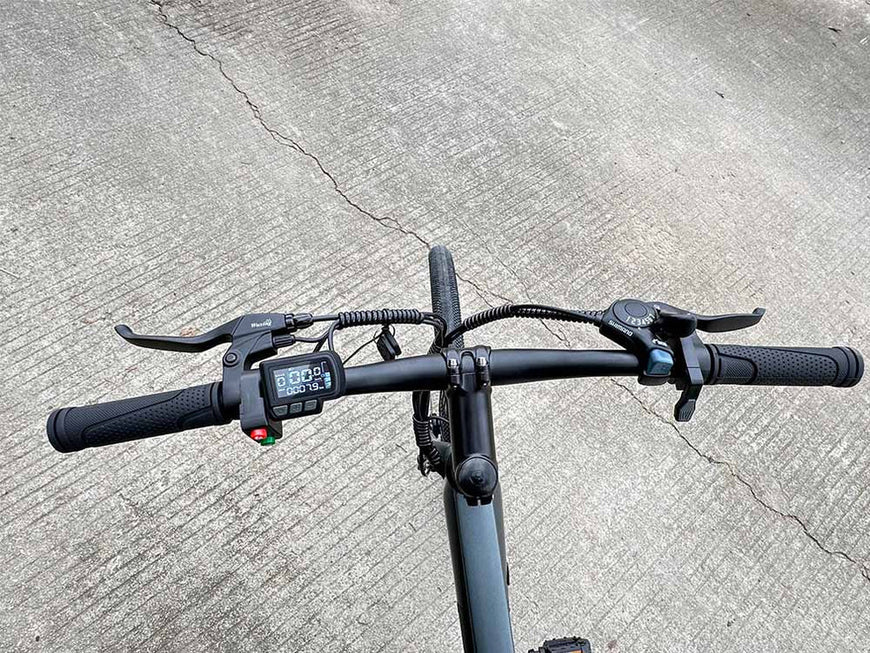 Close-up of bicycle handlebars with digital display on a concrete surface. Freego E7 Electric Bicycle For City Commuting