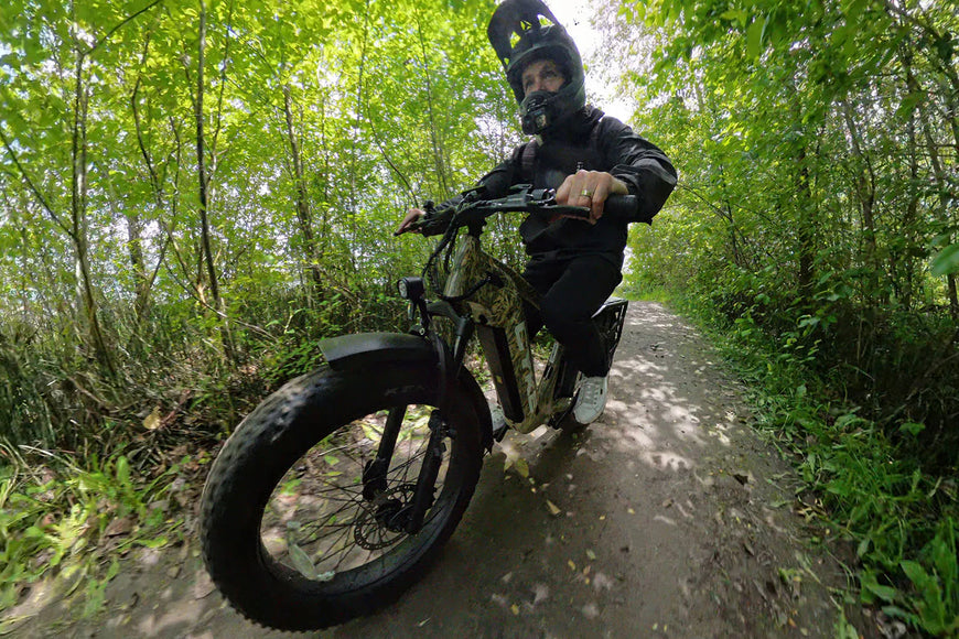 Person riding a fat-tire bike on a forest path. CYKE Cheetah Hunting EBike