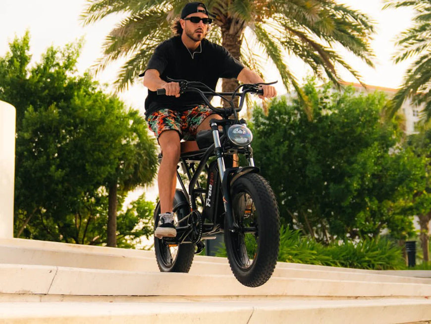 Man riding a bike on a concrete ledge with palm trees in the background. Freego Shotgun Prime F2 Pro Electric Cargo Bike