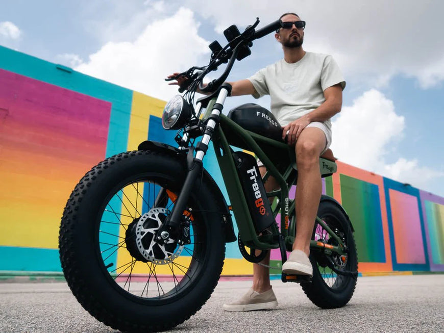 Man sitting on a green electric bike with a colorful mural in the background. Freego Flash F3 Pro Dual Motor and Battery eBike