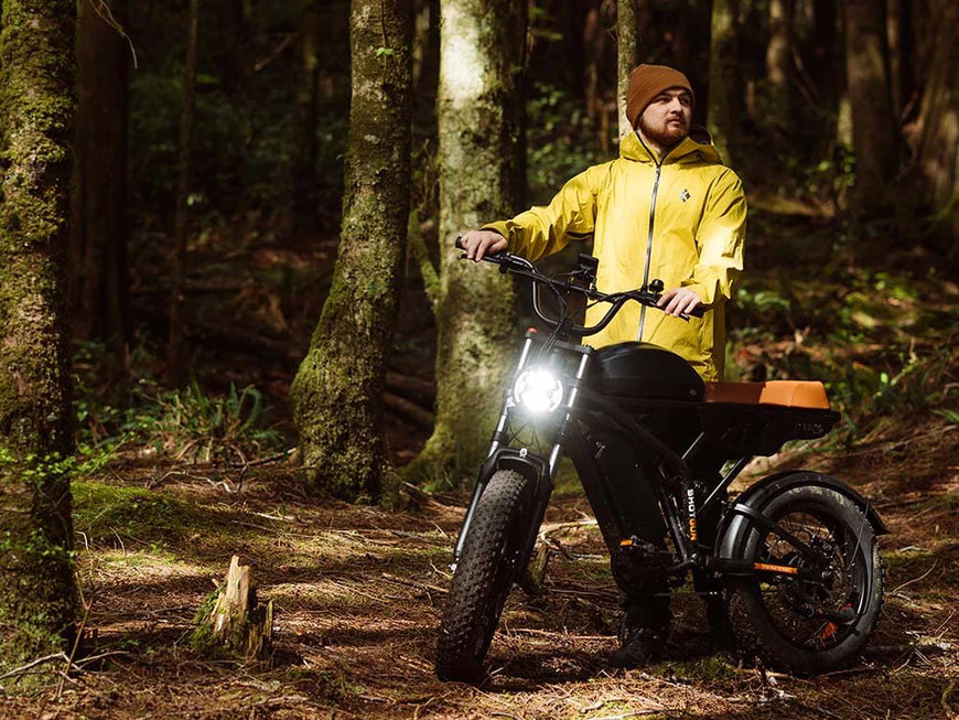 Person in a yellow raincoat standing next to an electric bike in a forest. Freego Flash F3 Pro Max Dual Motor and Battery eBike