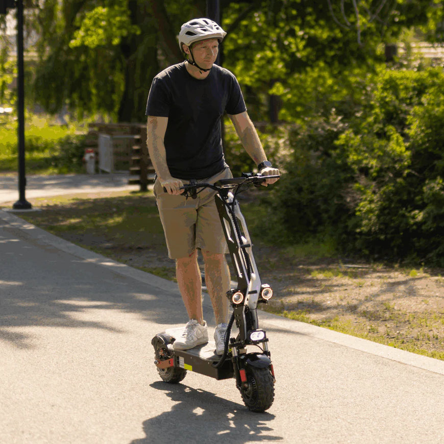 Man riding an electric scooter on a paved path with greenery in the background. Freego D11 Landtiger Electric Scooter Foldable Dual Motor 4000W