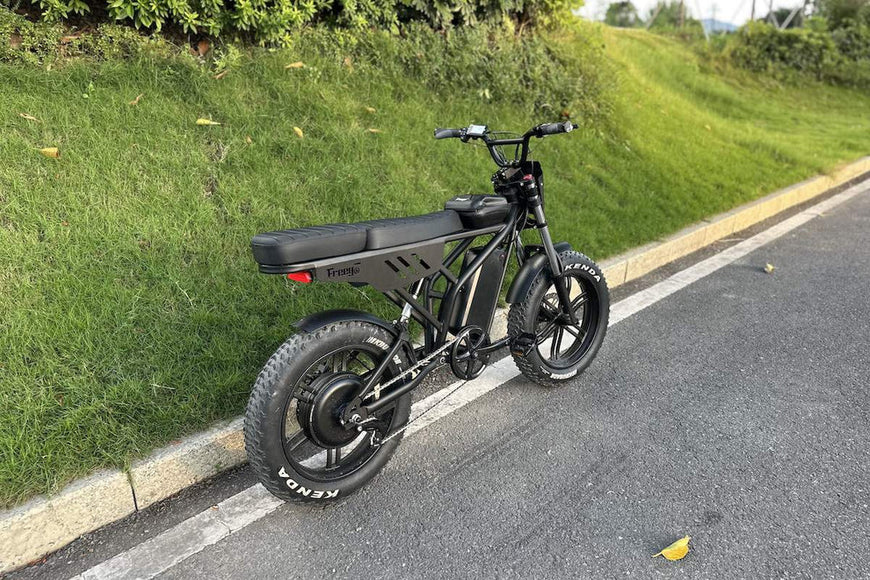 Black electric bike on a paved road with grass on the side. Freego Shotgun F2 Pro Max Prime Fat Tire E-Bike