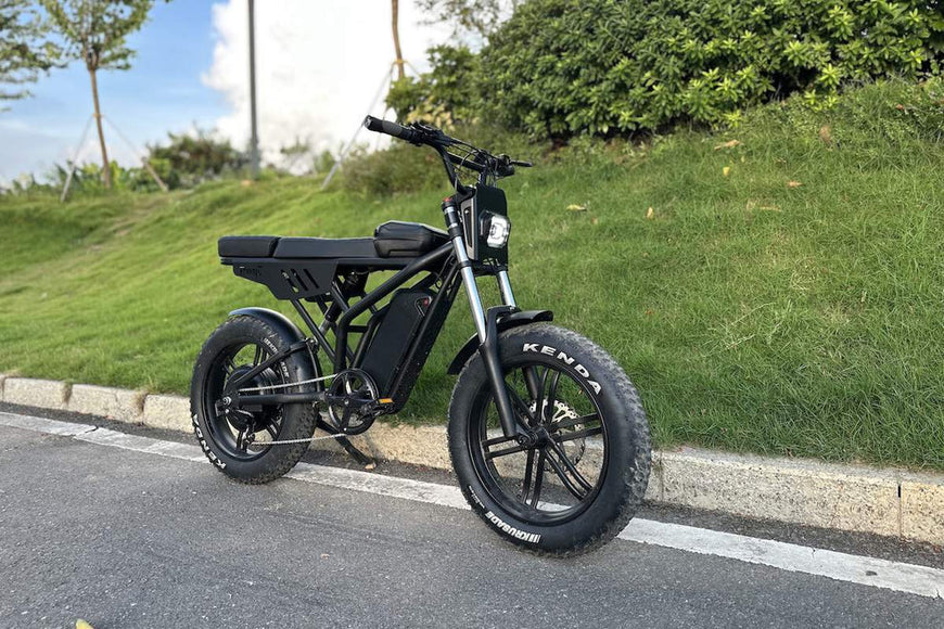 Black electric bike on a road with greenery in the background. Freego Shotgun F2 Pro Max Prime Fat Tire E-Bike