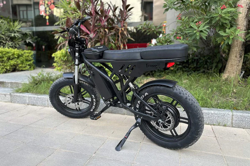 Black electric bike on a paved area with plants in the background. Freego Shotgun F2 Pro Max Prime Fat Tire E-Bike