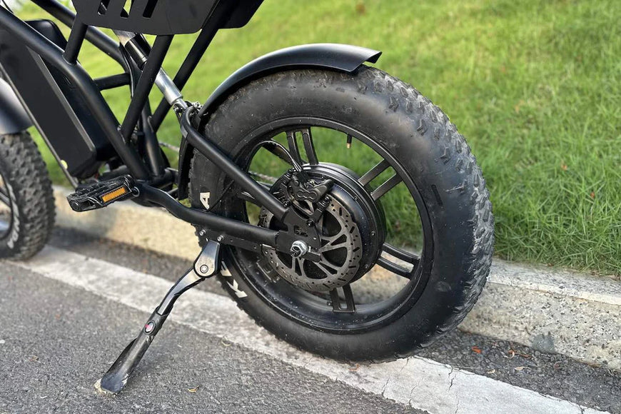 Close-up of a black electric bike tire on a road with grass in the background. Freego Shotgun F2 Pro Max Prime Fat Tire E-Bike