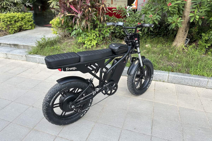 Black electric bike on a paved area with greenery in the background. Freego Shotgun F2 Pro Max Prime Fat Tire E-Bike