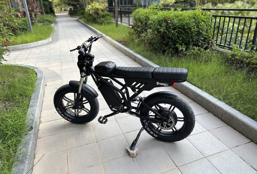 Black electric bike on a sidewalk with greenery in the background. Freego Shotgun F2 Pro Max Prime Fat Tire E-Bike