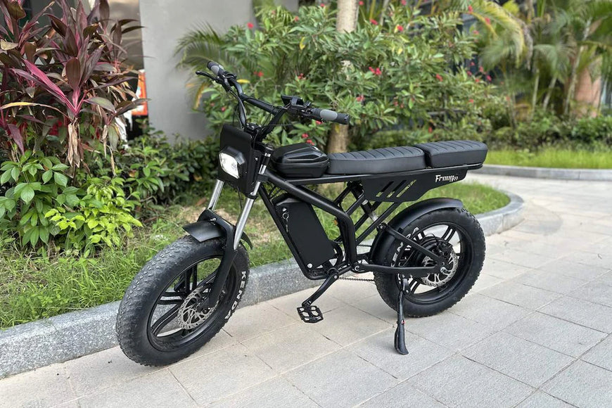 Black electric bike parked on a sidewalk with greenery in the background. Freego Shotgun F2 Pro Max Prime Fat Tire E-Bike