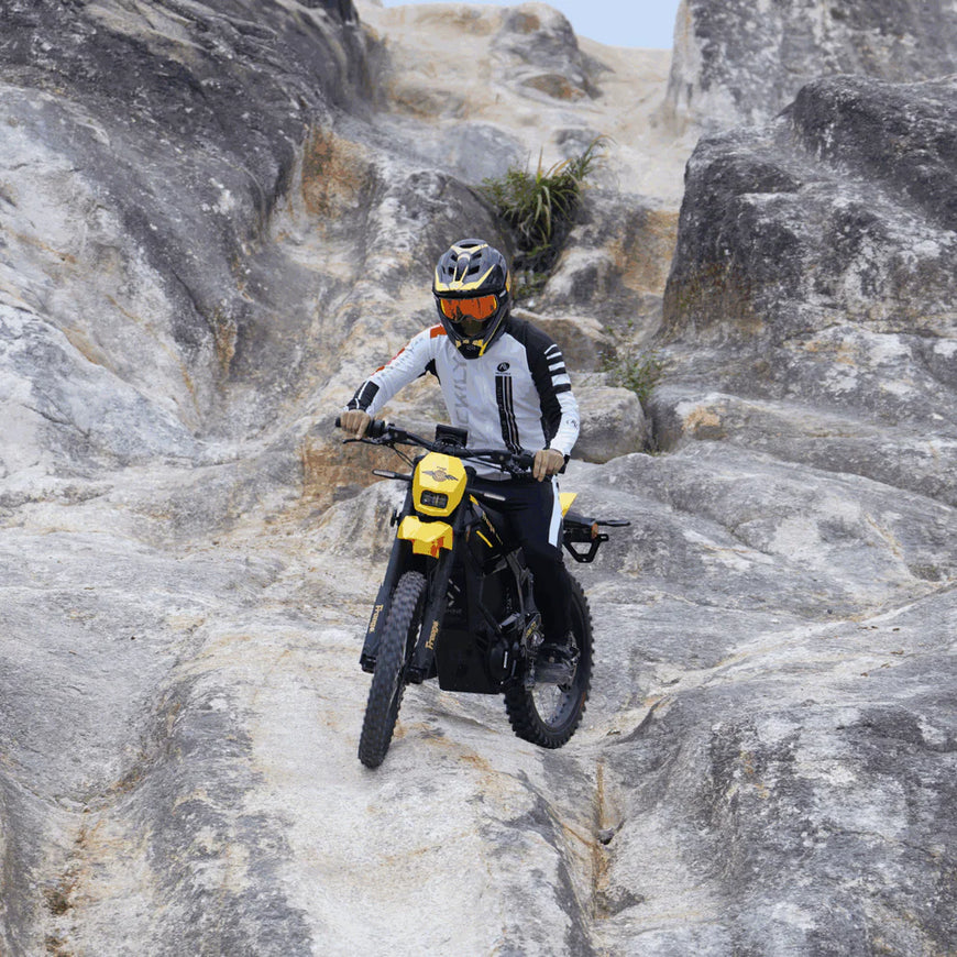 Person riding a yellow motorcycle on rocky terrain. Freego Nova 5 Mid-Drive Off-Road Electric Dirt Bike