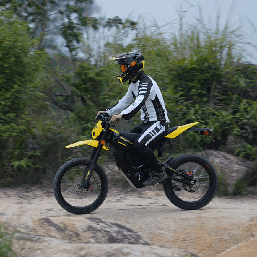 Person riding a yellow and black dirt bike on a trail with greenery in the background. Freego Nova 5 Mid-Drive Off-Road Electric Dirt Bike