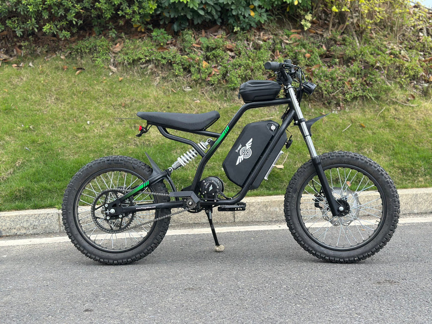 Black electric bike on a road with grass and trees in the background. Freego Nova 3 Mid-Drive All-Terrain Dirt eBike